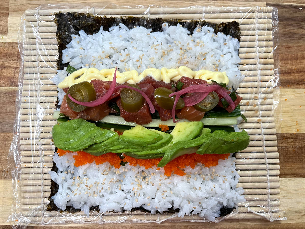 all ingredients placed over a nori sheet on a bamboo mat
