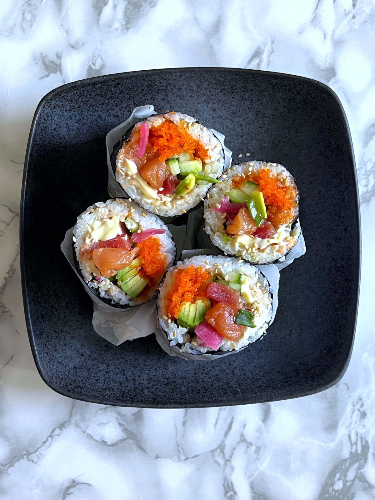 top view of four sushi burritos on a plate