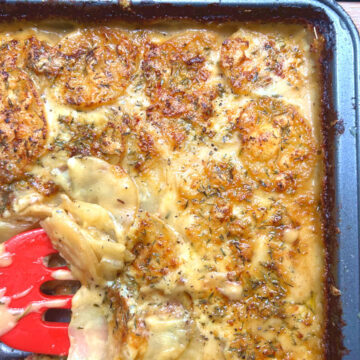 scooping a slice of potatoes au gratin from the baking tray