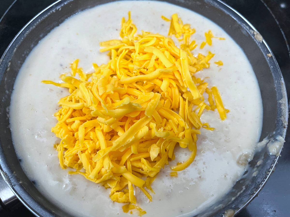 creamy sauce in a pan with unmelted cheese on top of the sauce