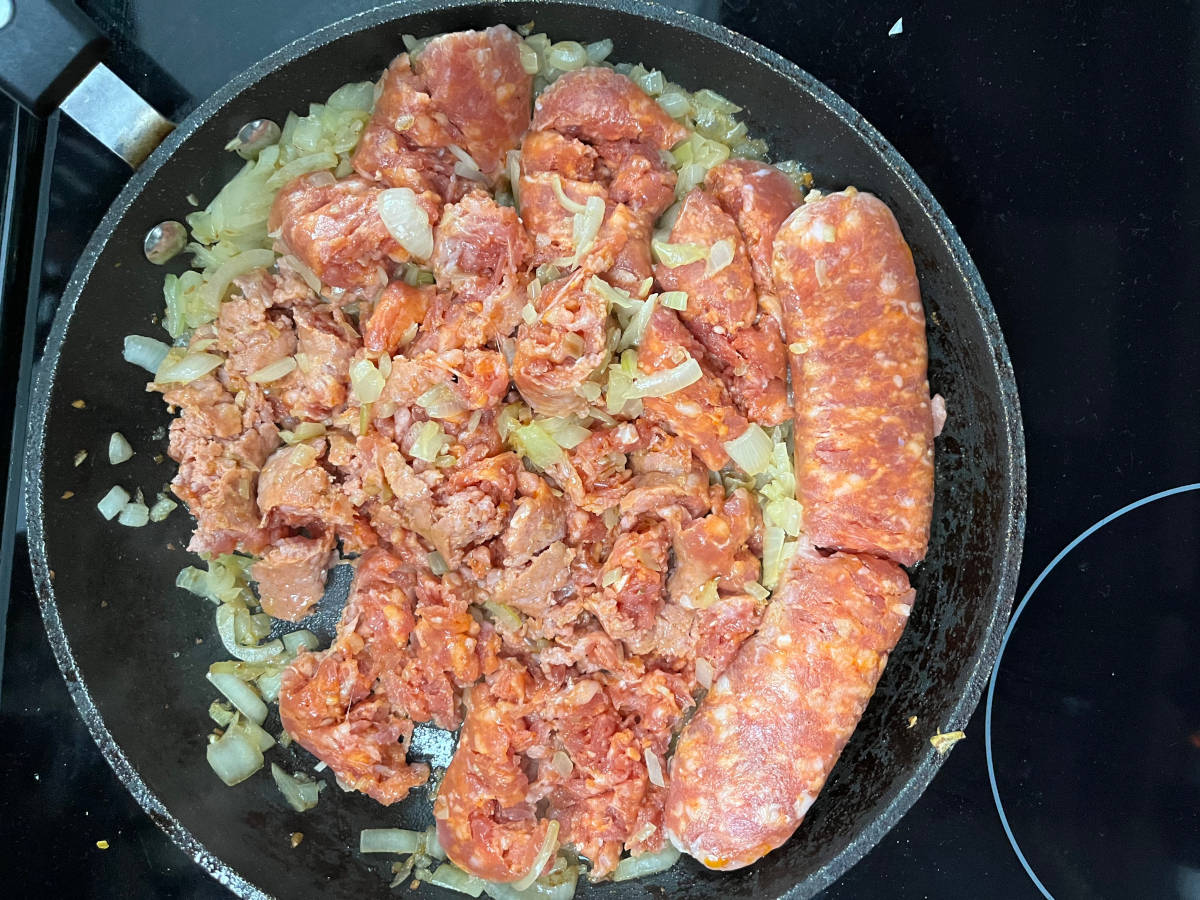Cooking the Italian sausage with sautéed garlic and onions in a pan