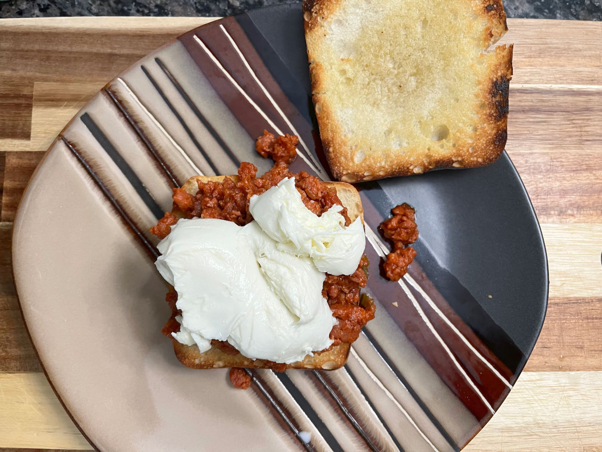 Sloppy joe filling on one side of the bun topped with mozzarella cheese