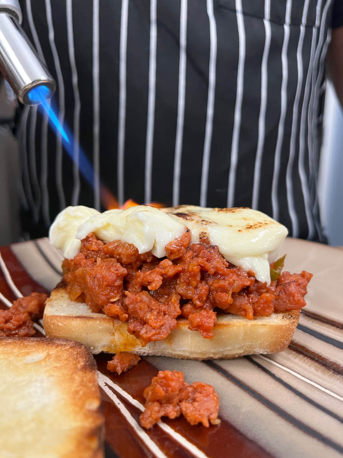 Melting the mozzarella cheese over the sloppy joe filling with a blowtorch