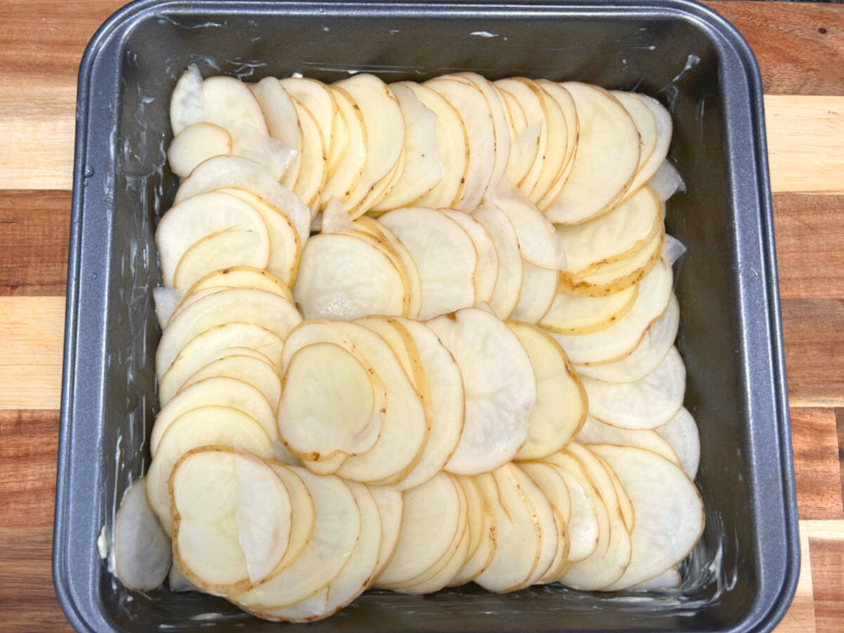 thinly sliced potatoes in a baking dish