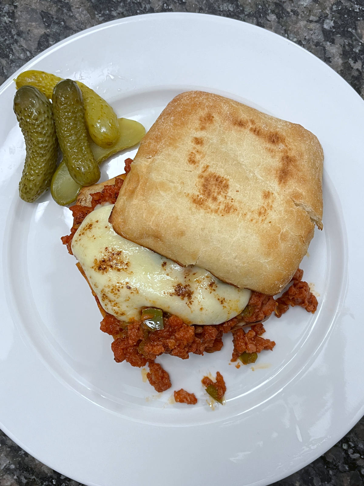 Top view of sloppy joes with some pickles on the side
