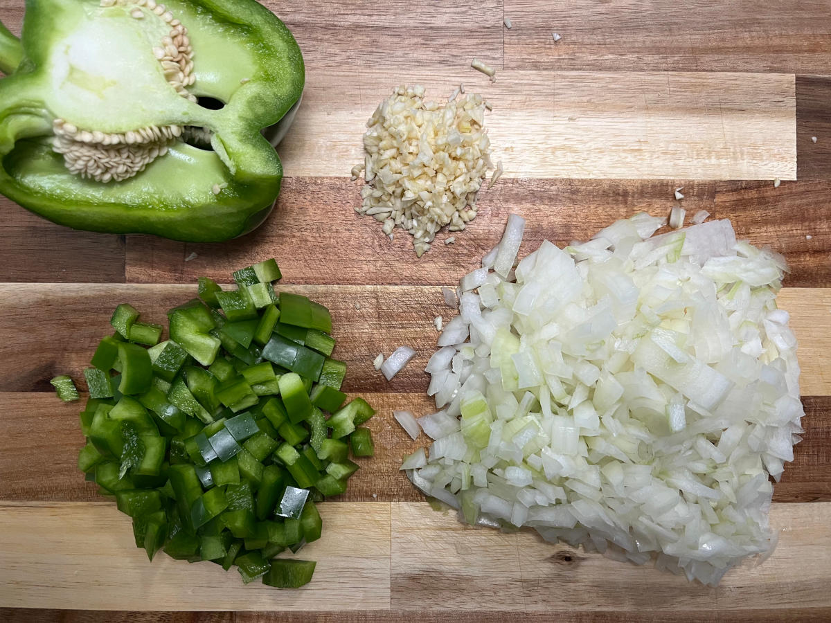 Chopped garlic, green bell pepper and onions on a cutting board