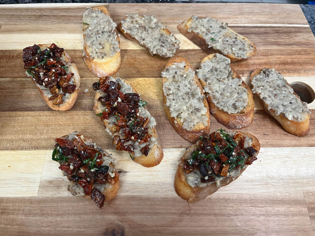 Applying the mixture of sun-dried tomatoes and other ingredients over the Baba Ganoush slice