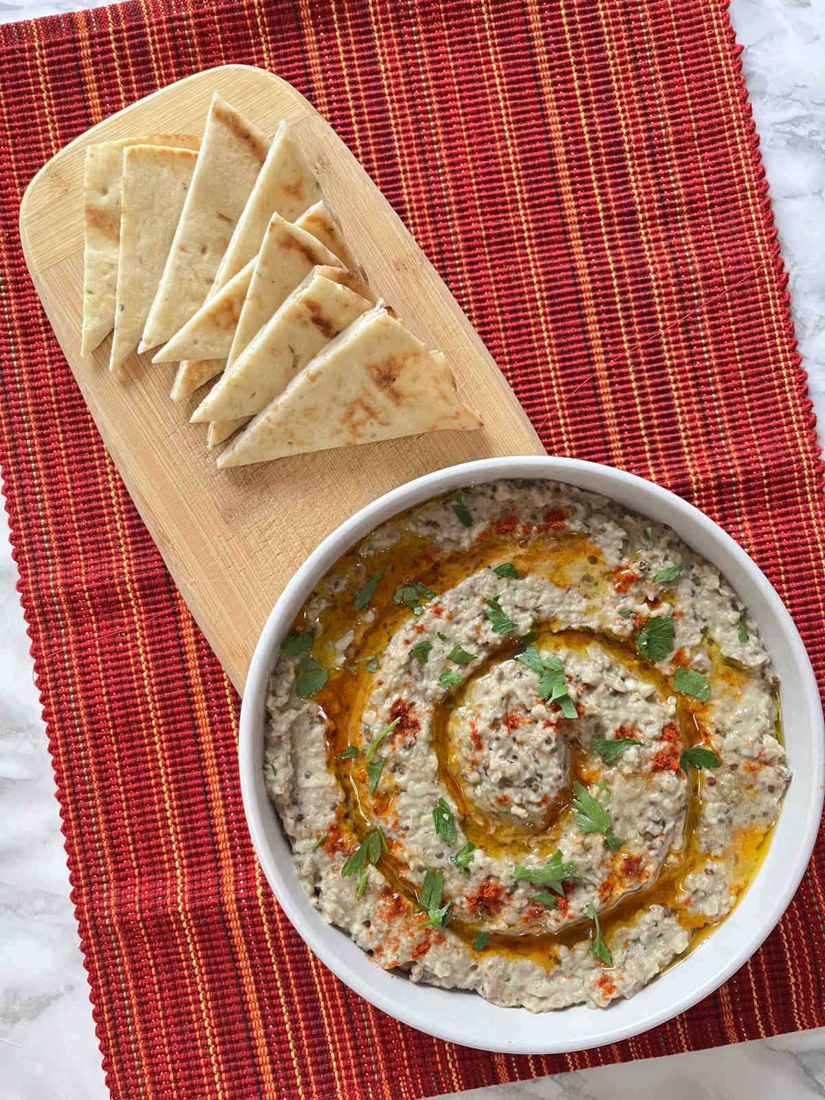 Baba Ganoush in a serving bowl with few slices of pita bread on the side