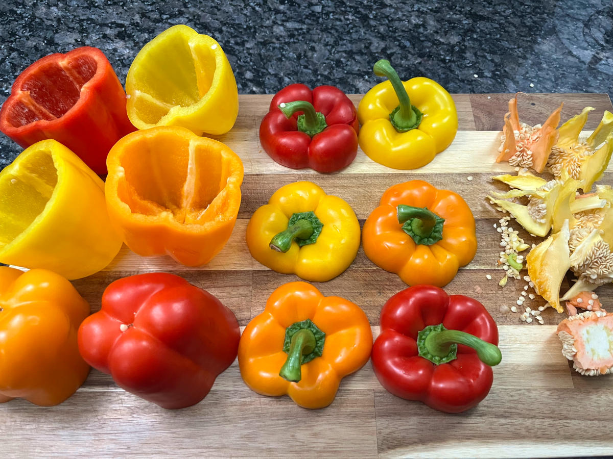 six bell peppers on a cutting board with their tops cut off