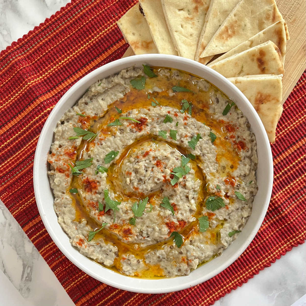 Baba Ganoush in a serving bowl with few slices of pita bread on the side