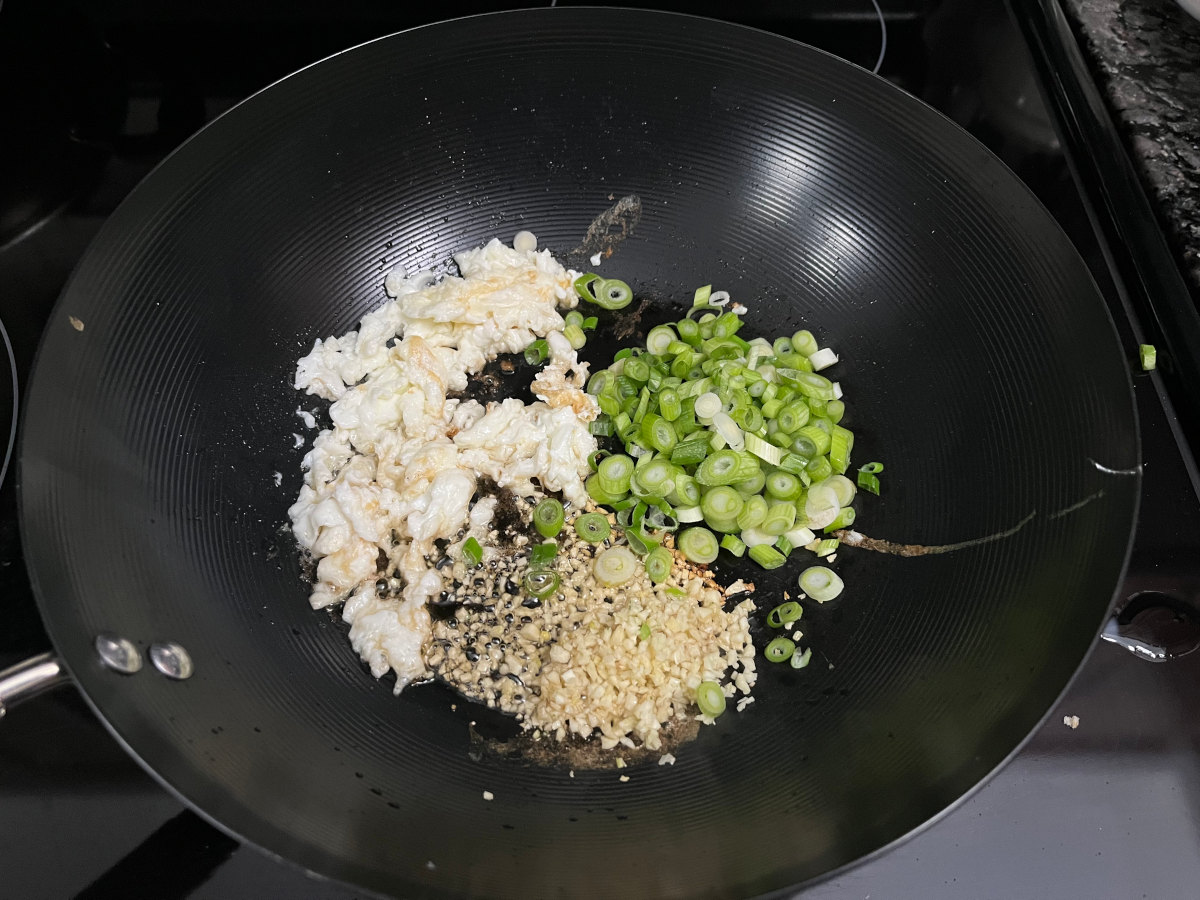 Fried egg and sautéed garlic and onion in a wok