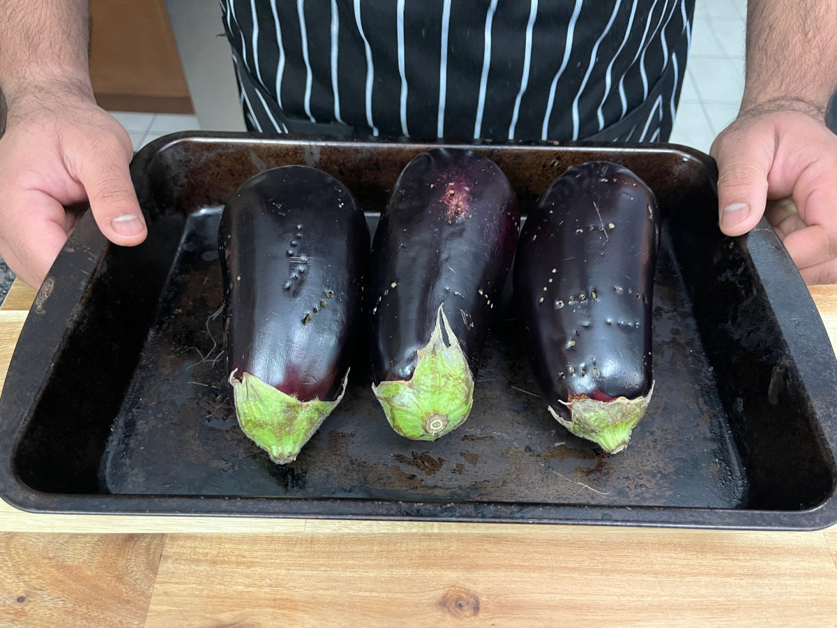 Three uncooked eggplants in a baking tray
