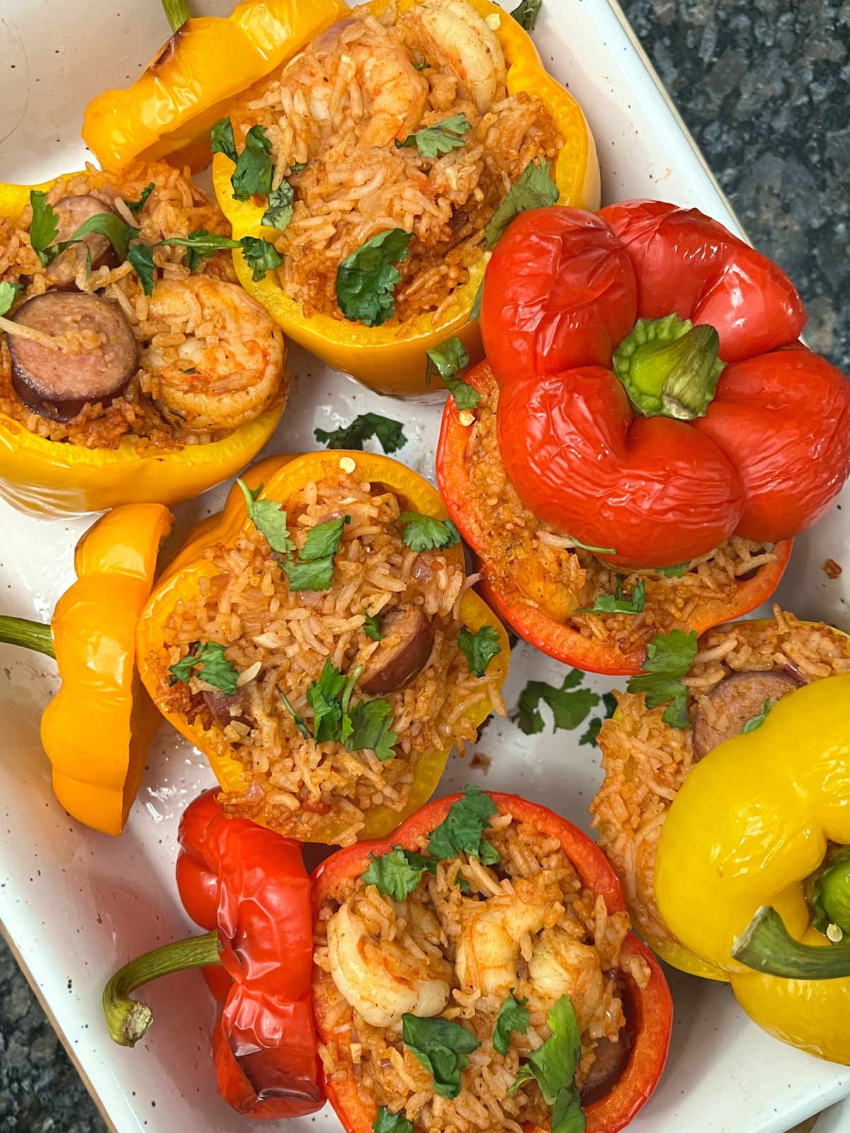 six jambalaya stuffed peppers in a baking dish
