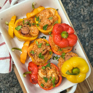 six jambalaya stuffed peppers in a baking dish