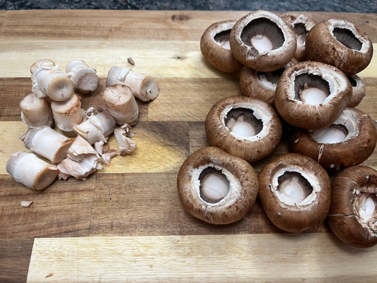 mushroom stems and caps separated on a cutting board