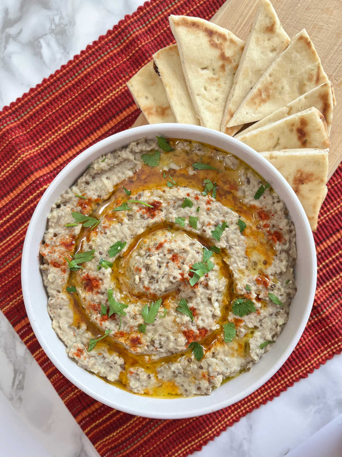 Baba Ganoush in a serving bowl with few slices of pita bread on the side