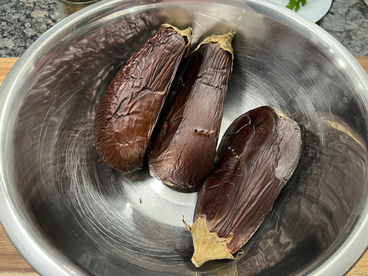 Three roasted eggplants in a bowl