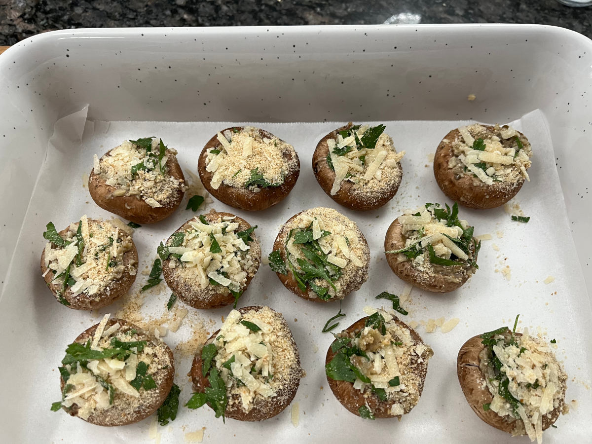 stuffed mushrooms in a baking dish topped with a mixture of parmesan bread crumbs