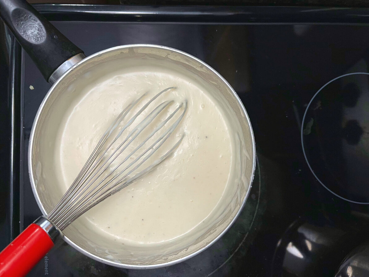 béchamel sauce in a pan with a whisk