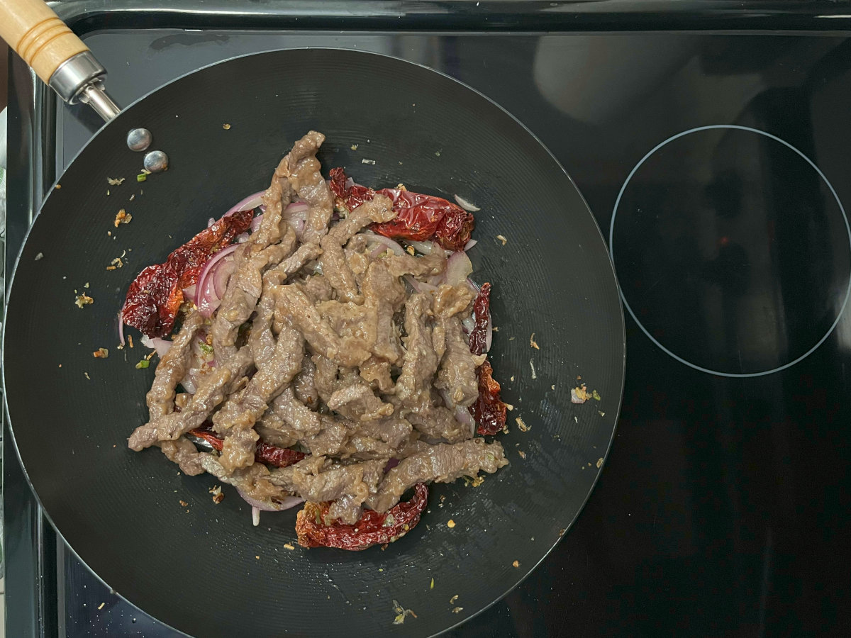 Beef and other regular ingredients frying in a wok