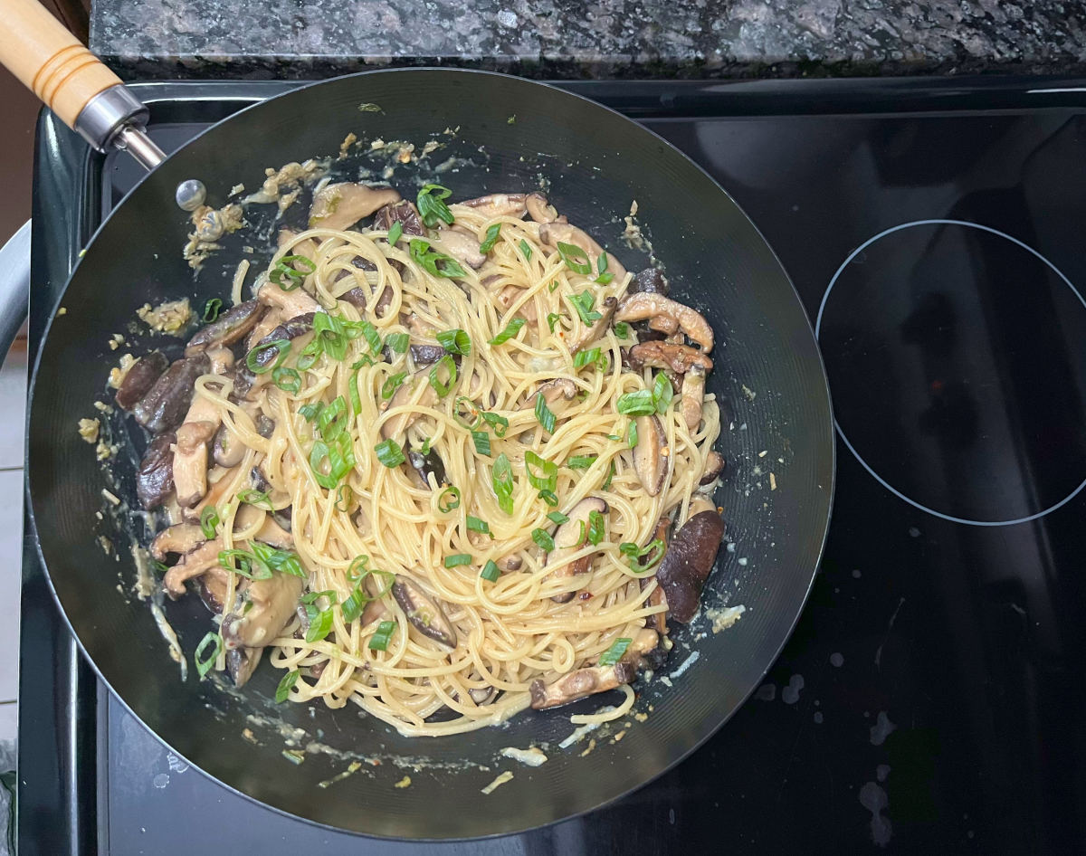 chopped spring onions added to the wok of miso mushroom pasta