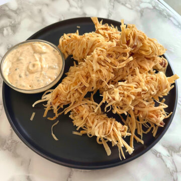 crispy thai thread chicken in a plate with a bowl of sriracha mayo on the side