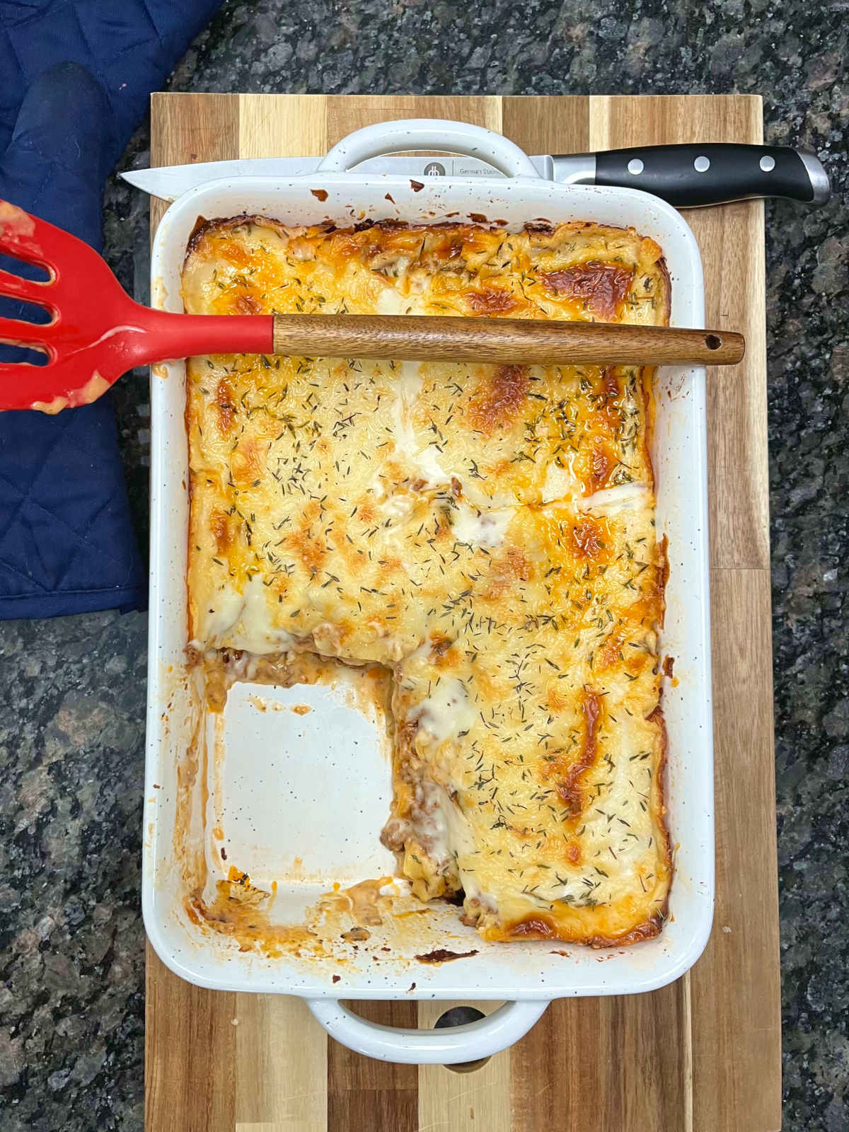 baked Greek moussaka lasagna in a casserole dish with a spatula on top of the dish