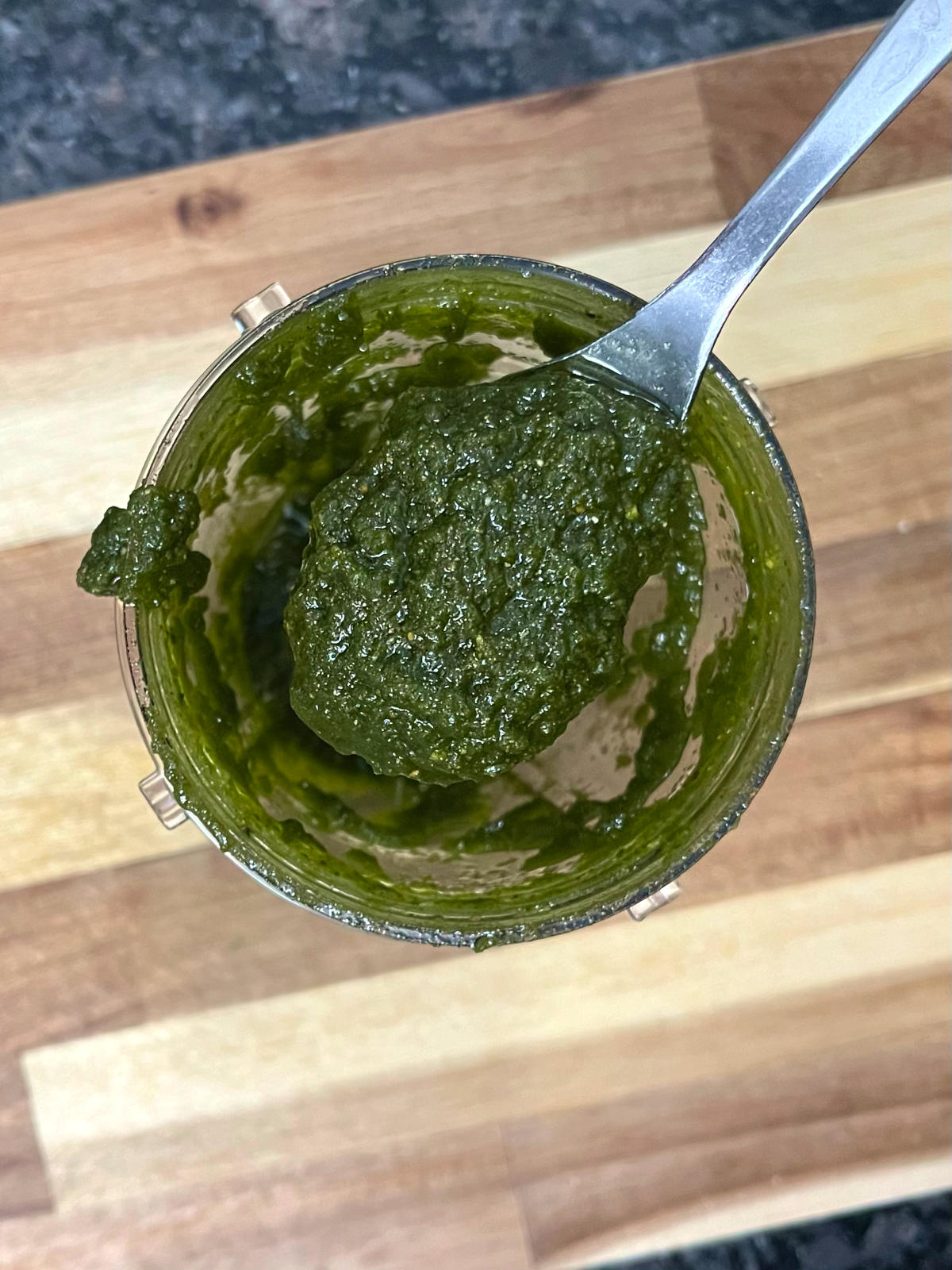 spoon of pistachio basil pesto taken out from the blender