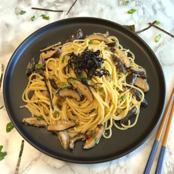 miso mushroom pasta on a plate with a pair of chopsticks placed diagonally besides the plate