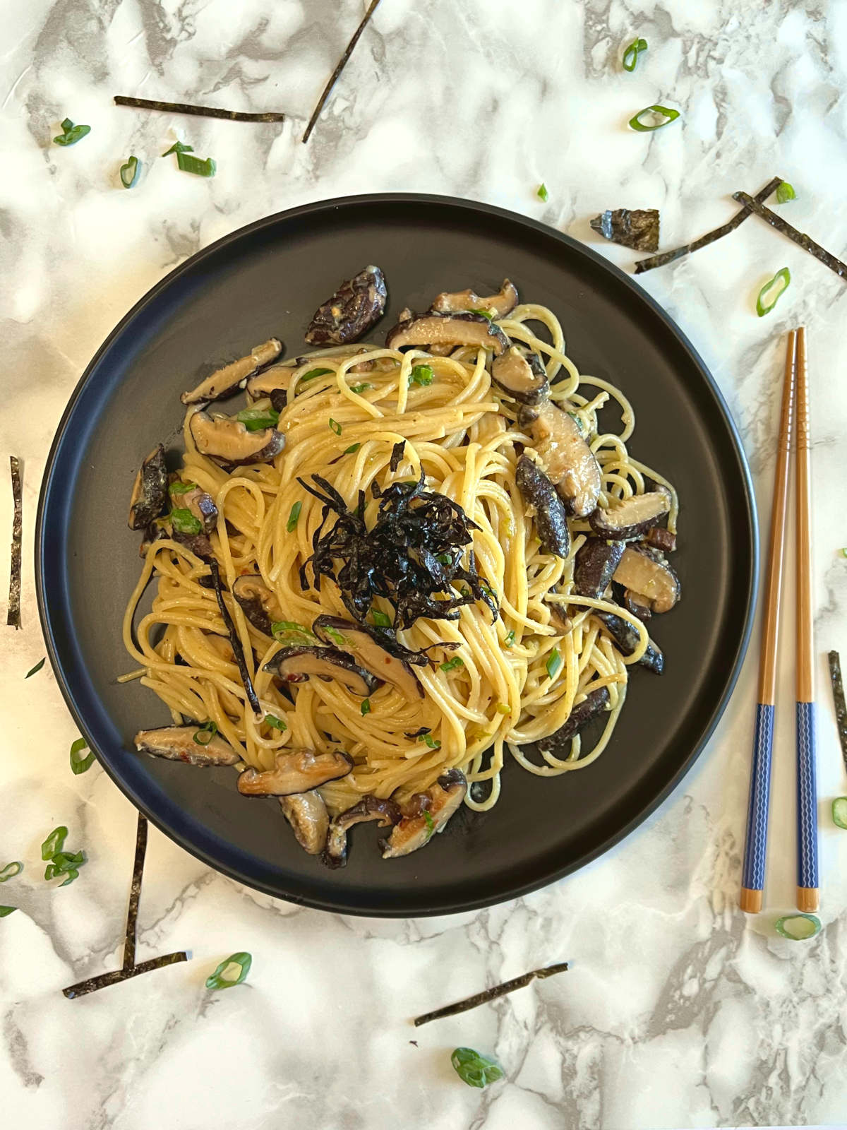 miso mushroom pasta on a plate with a pair of chopsticks on the side