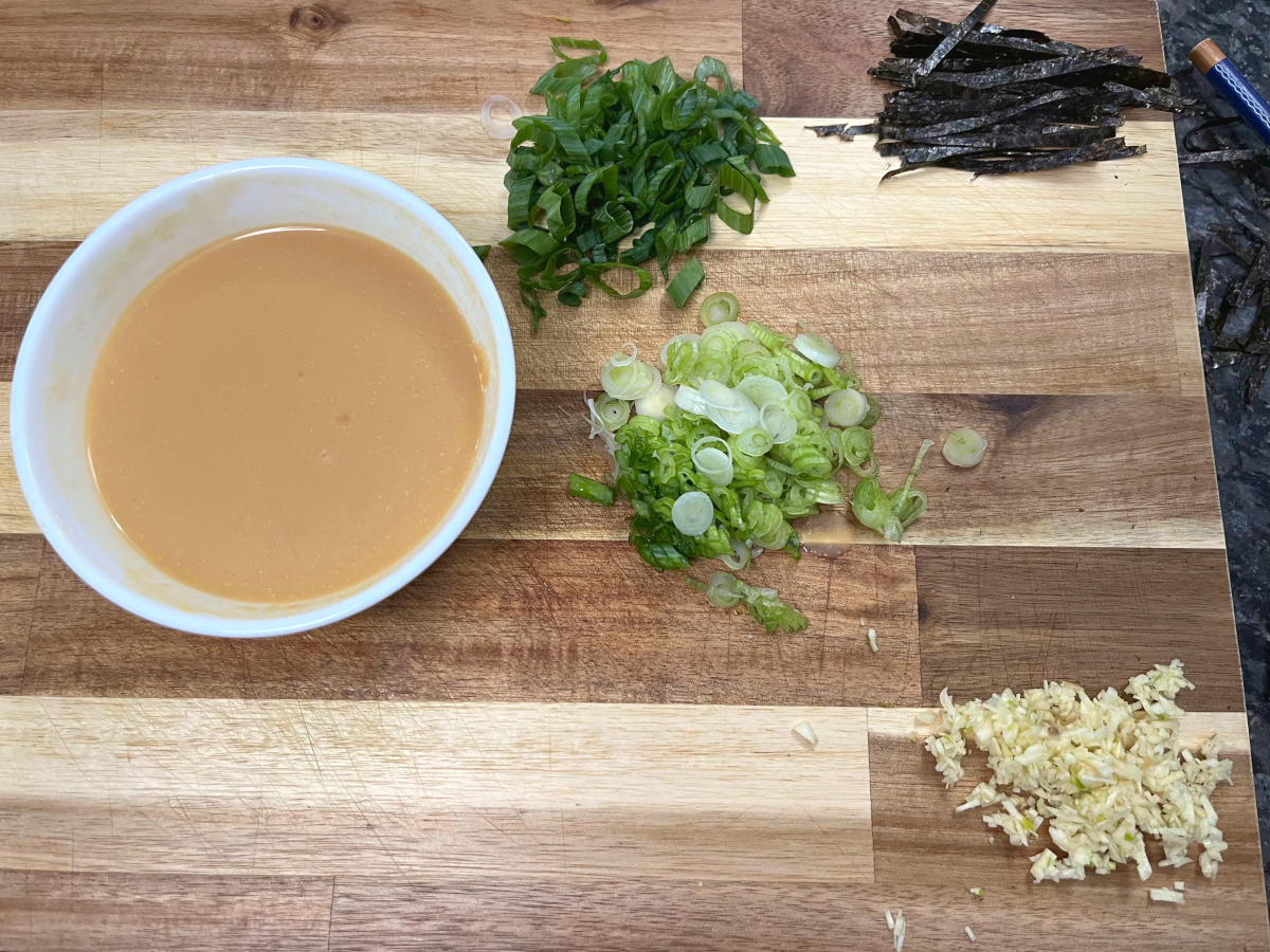 miso paste, chopped spring onions and garlic, with thinly sliced nori on a cutting board