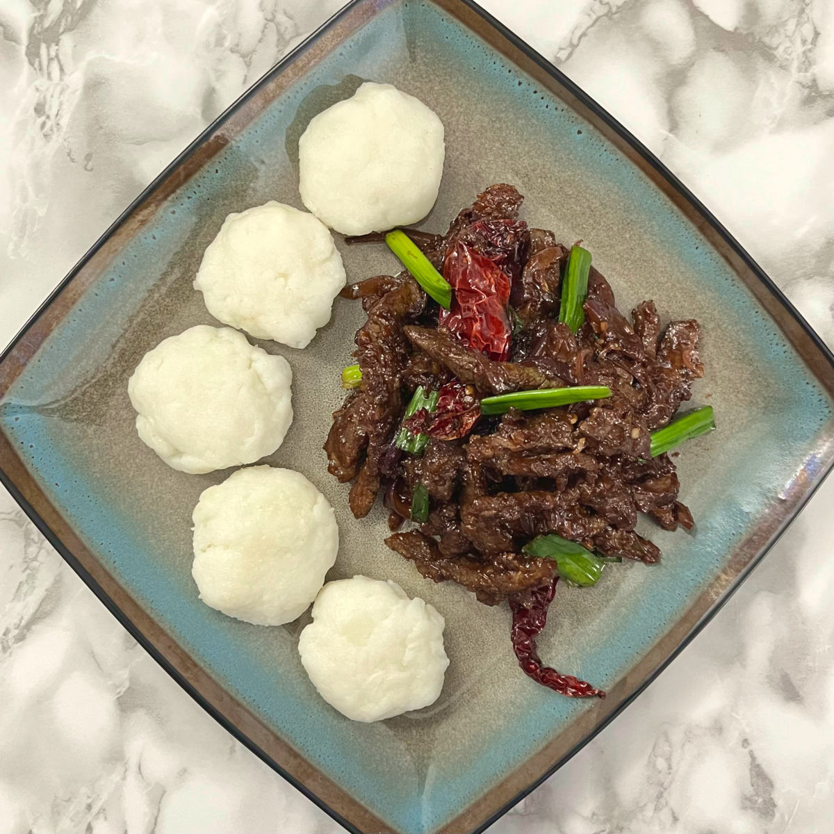 Mongolian beef in a square plate with five morsels of ugali