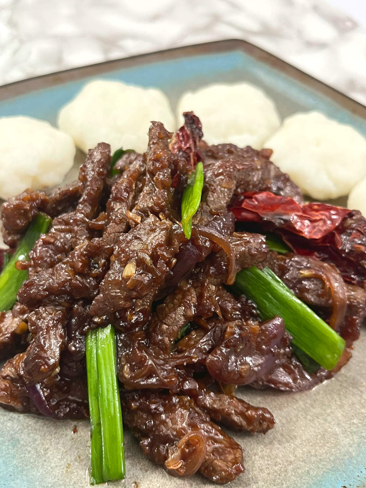 close up shot of Mongolian beef on a plate with five morsels of Ugali