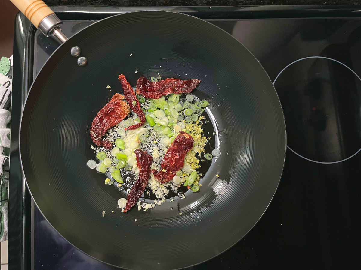 regular ingredients like red chilies, green onions, ginger and garlic frying in a wok