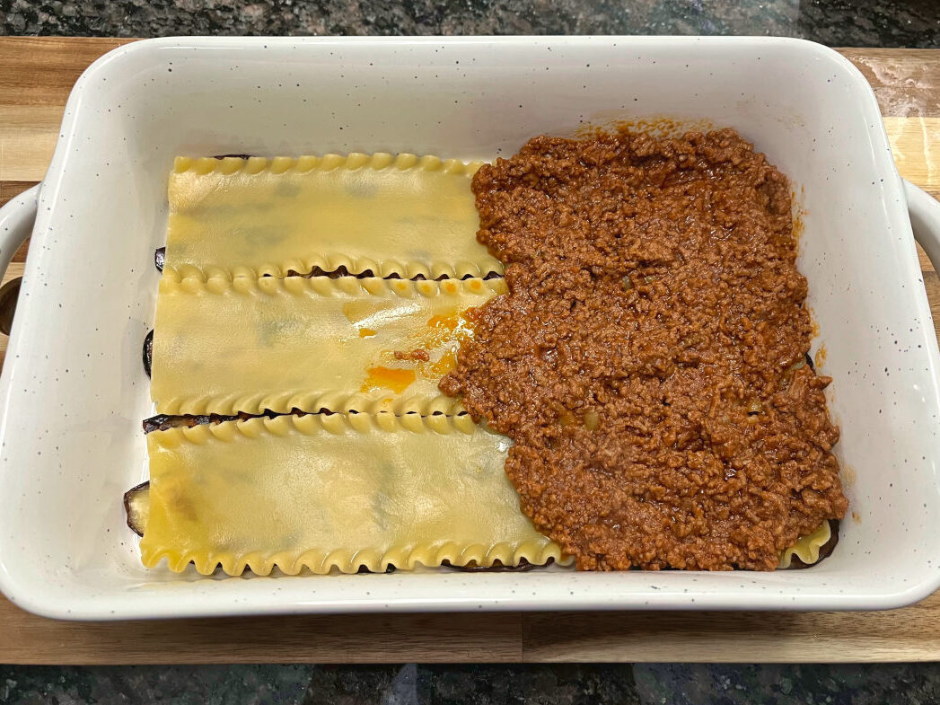 cooked pasta and meat sauce layer in a casserole dish