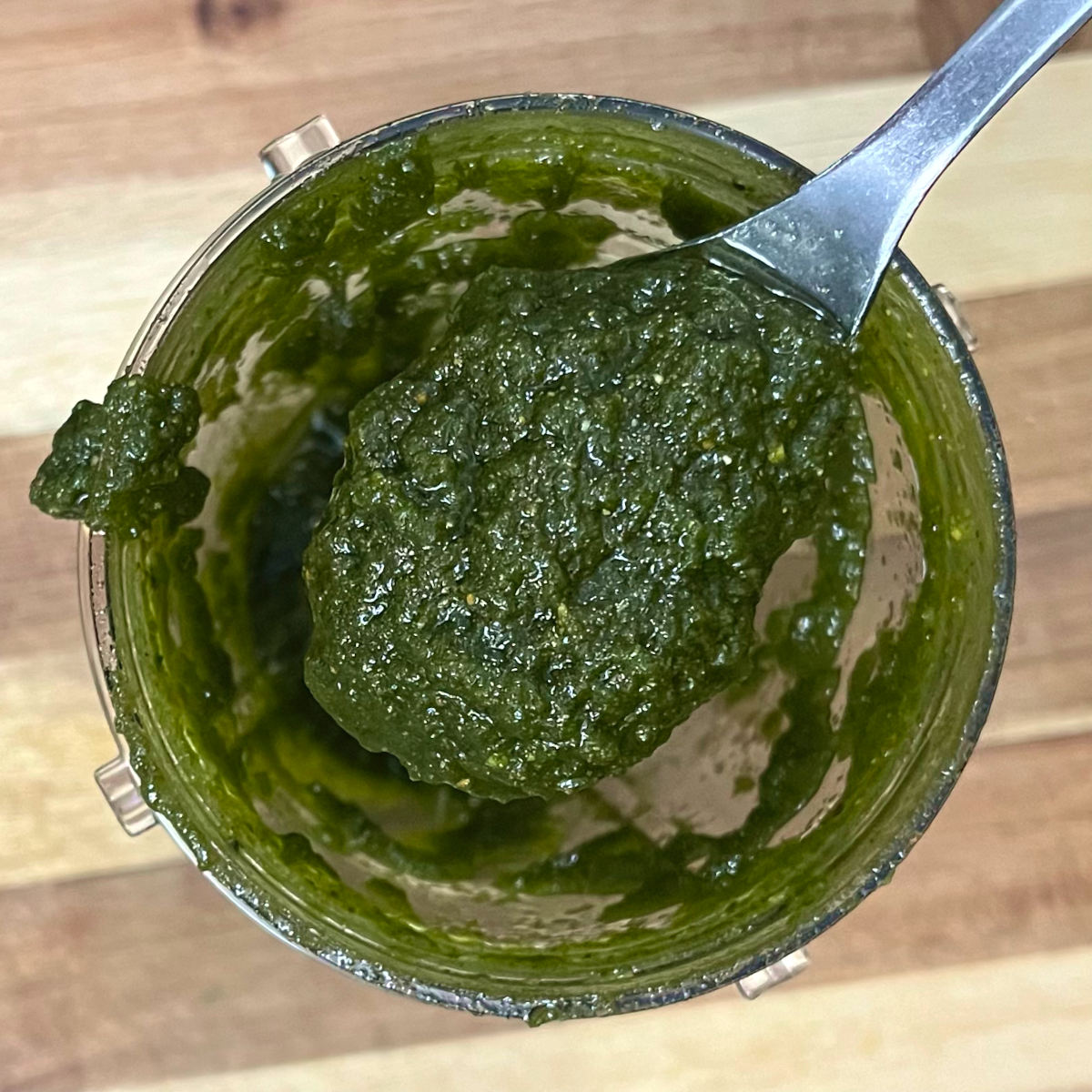 spoon of pistachio basil pesto taken out from the blender