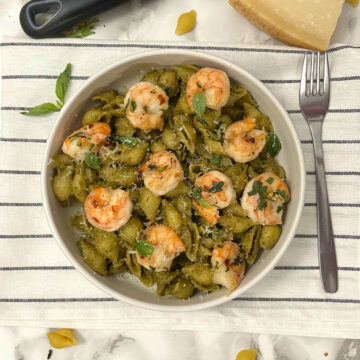 pistachio pesto shrimp pasta in a bowl with a fork on the side