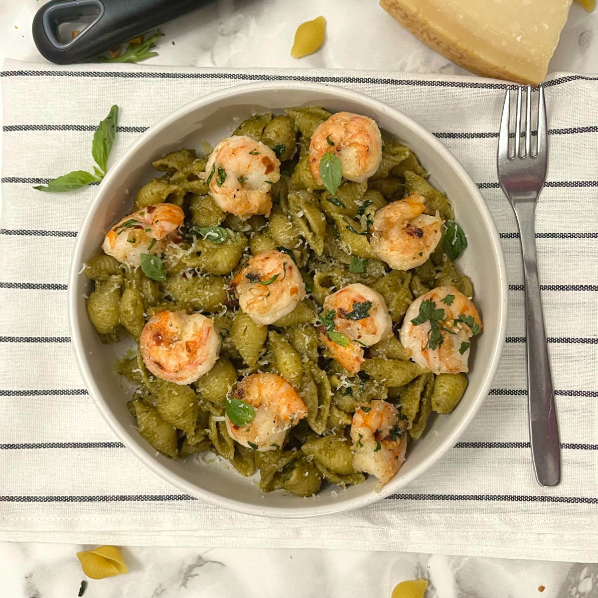 pistachio pesto shrimp pasta in a bowl with a fork on the side