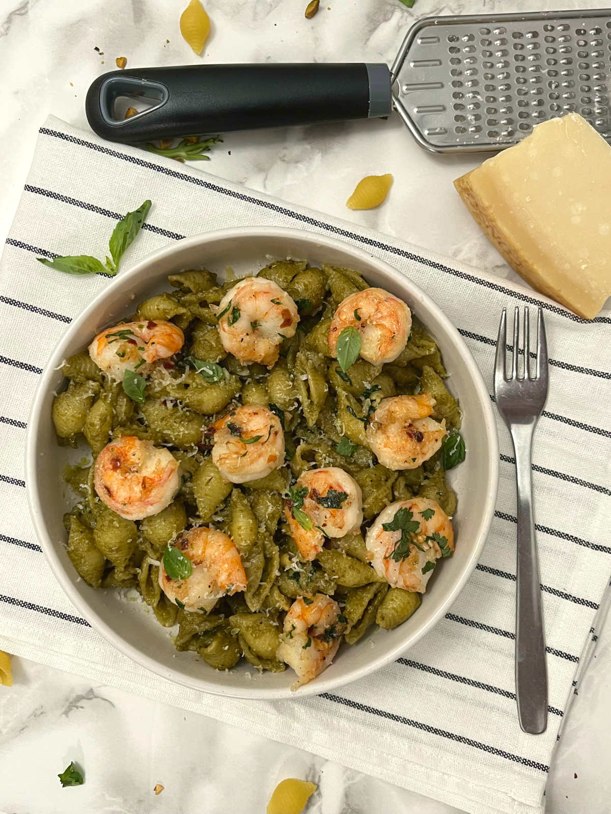 pistachio pesto shrimp pasta in a bowl with a fork on the side