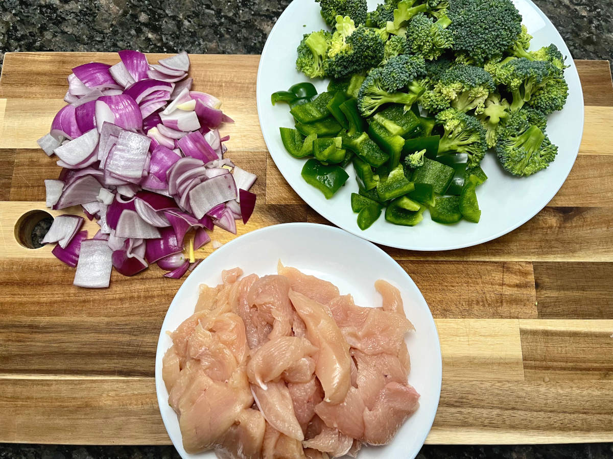 raw chicken sliced, along with chopped onions, green bell peppers and broccoli
