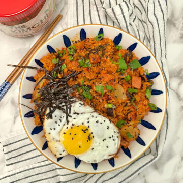 kimchi fried rice in bowl with chopsticks and a jar on the side