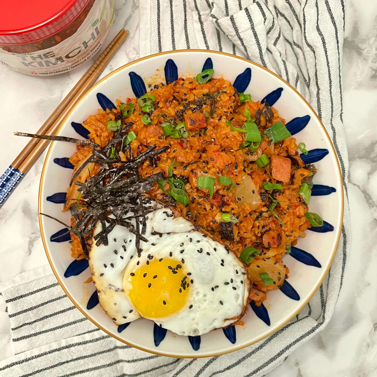 kimchi fried rice in bowl with chopsticks and a jar on the side