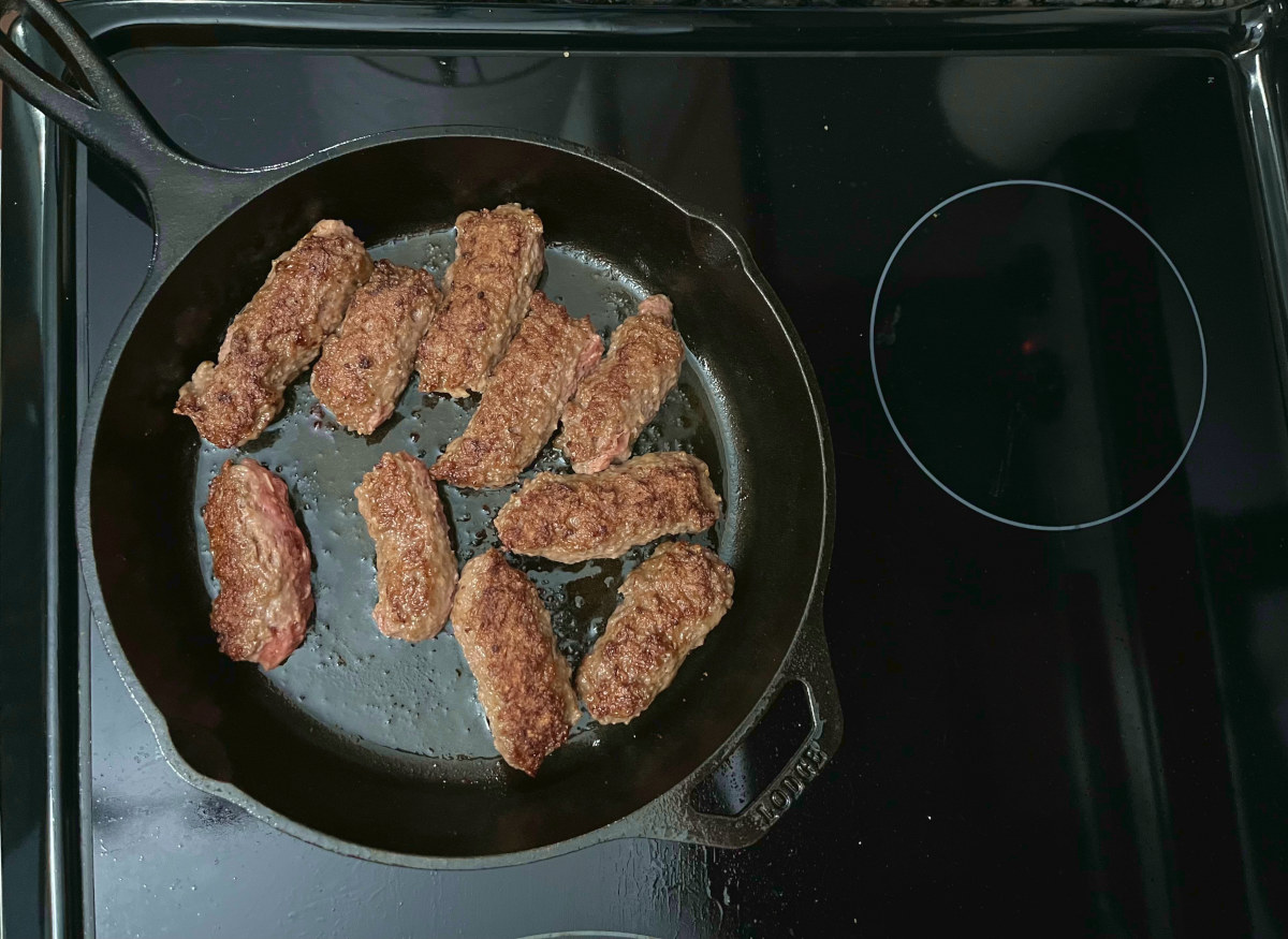 cooking the Balkan sausages in a skillet