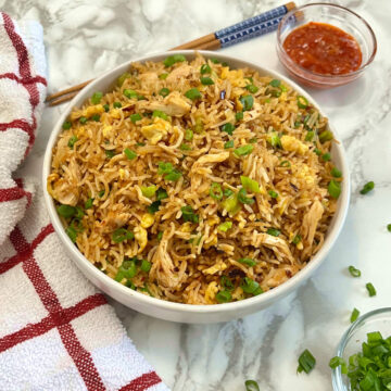burnt garlic fried rice in a bowl with some schezwan sauce and chopsticks on the side