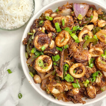 spicy stir fry squid on a plate with a bowl of rice on the side