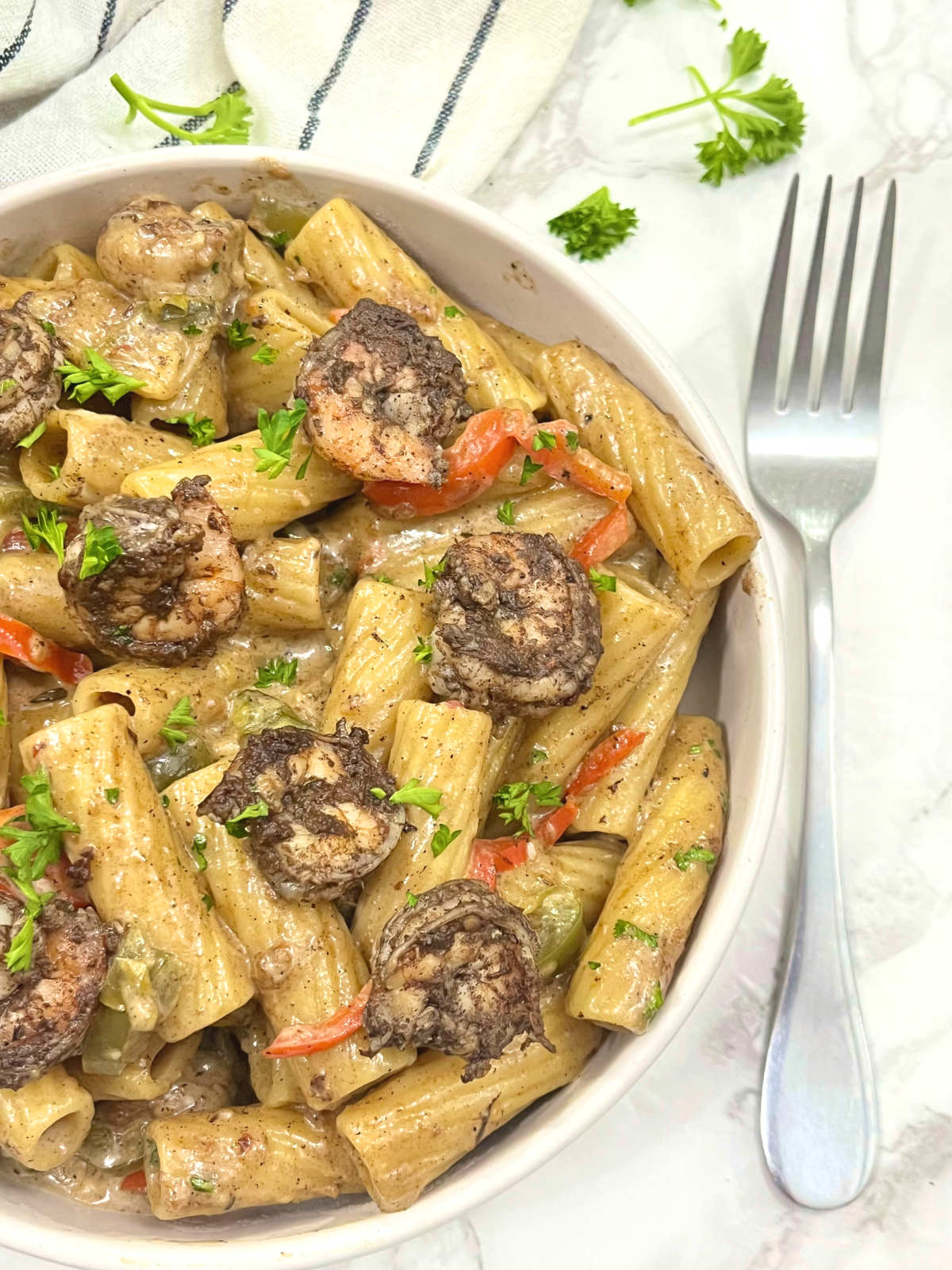 jerk shrimp pasta in a bowl with a fork on the side
