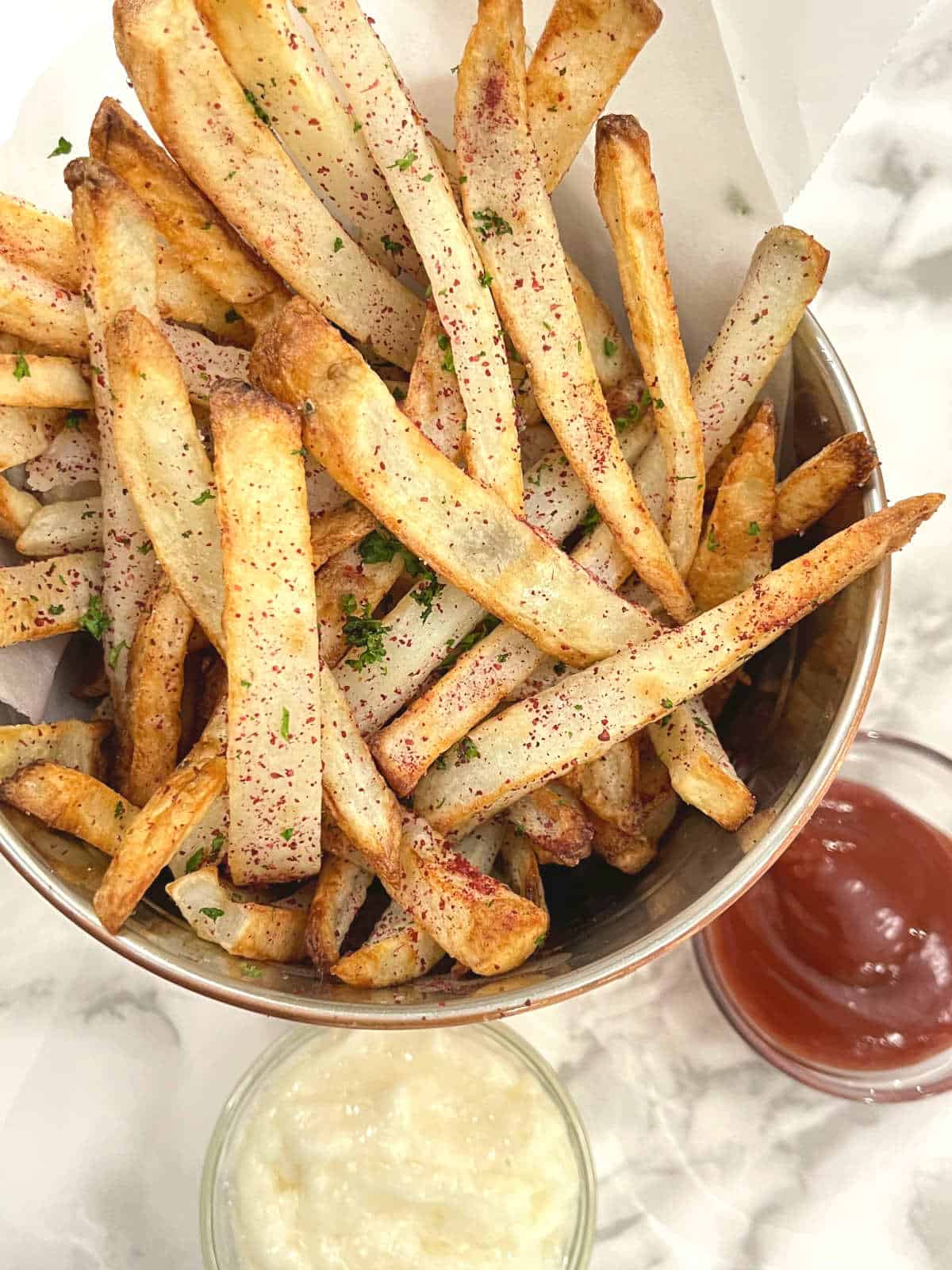 sumac fries in a bucket with toum and ketchup on the side