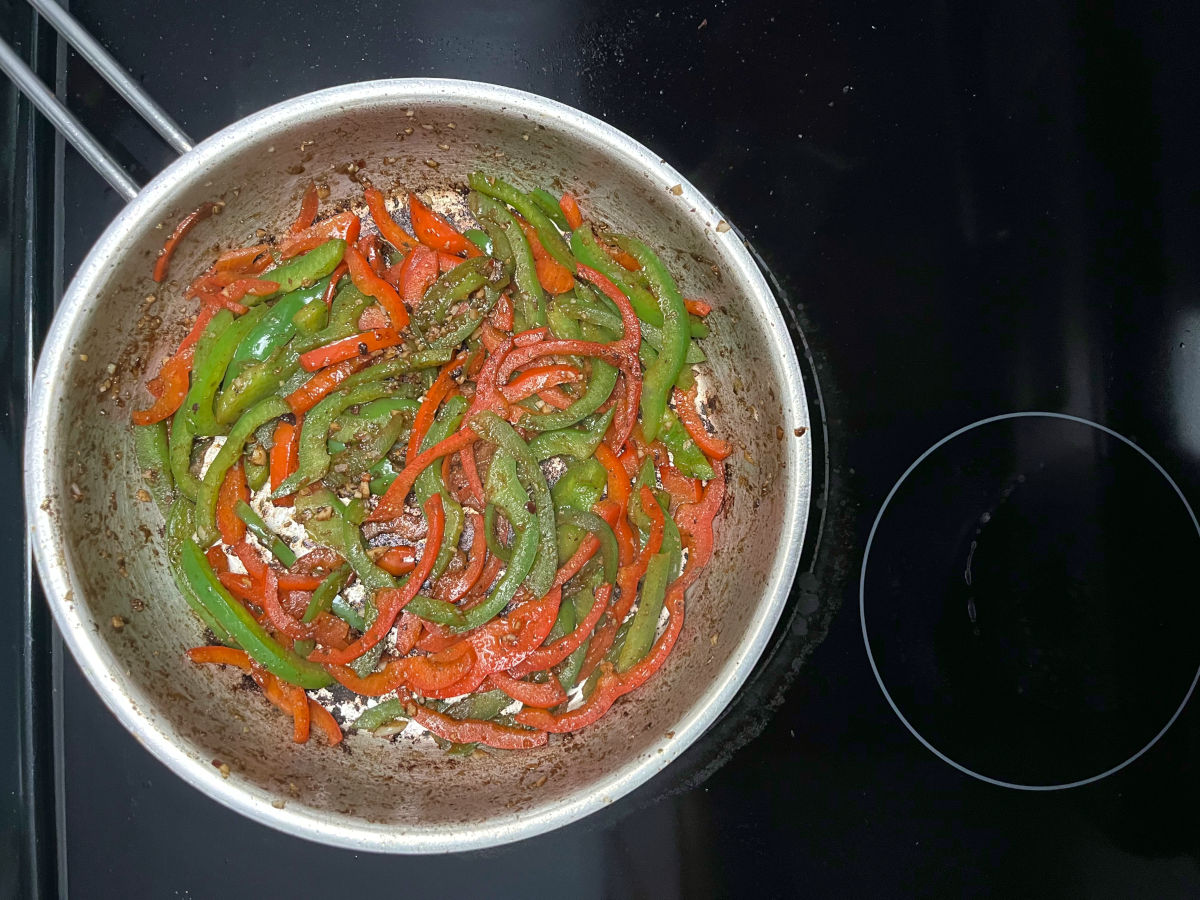 sliced bell peppers sautéed in a pan