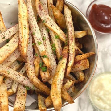 sumac fries in a bucket with toum and ketchup on the side