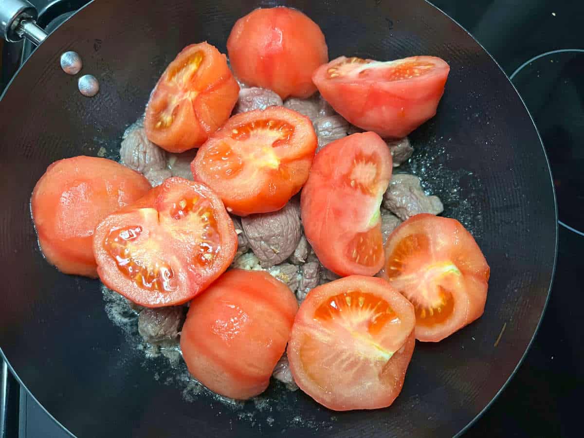 tomatoes, beef chunks and minced garlic on a pan